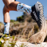 Person running on a trail wearing Terrex hiking boots and Christmas socks.